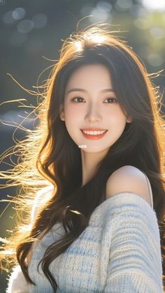 Woman with long hair and an off-shoulder sweater smiling with backlight