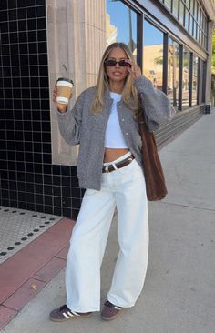 Woman in a crop top and wide leg pants holding a coffee cup on a street