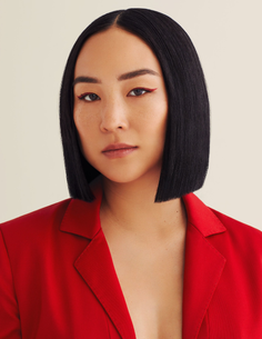 Woman with short black hair and red eyeliner wearing a red blazer