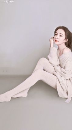 Woman in an off-shoulder sweater and tights sitting on the floor