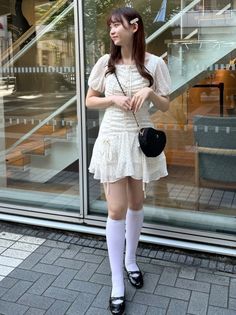 Woman in a white polka dot dress and knee-high socks outdoors