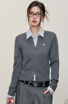 Woman wearing glasses, a grey cardigan, and a striped shirt