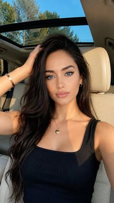 Woman with long dark hair and blue eyes in a car with a sunroof