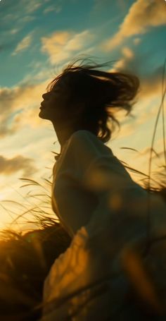 Woman with long hair in motion against a golden hour sky