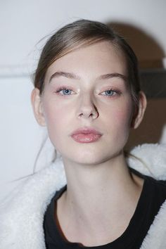 Woman with blue eyes and natural makeup wearing a white fluffy jacket