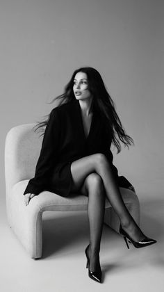 Woman in a black blazer and pantyhose sitting in a studio