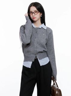 Woman in a gray cardigan and striped shirt holding glasses
