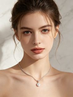 Woman with an updo hairstyle wearing a silver necklace with a pendant