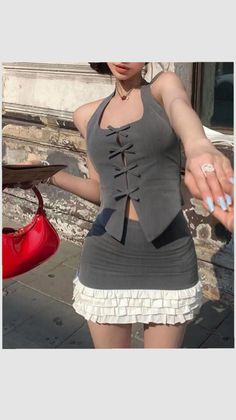 Woman in a gray halter top and mini skirt with a red handbag outdoors