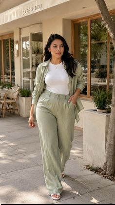Woman in a light green outfit walking past a cafe on a sunny day