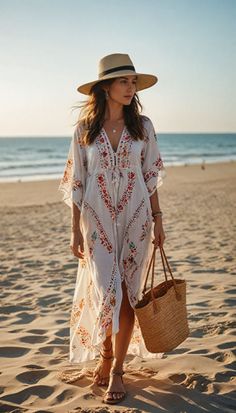 Woman in an embroidered dress and straw hat walking on a beach at golden hour