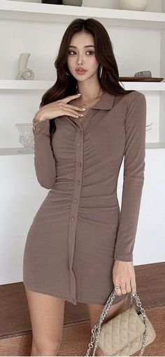 Woman in a brown long-sleeve collared dress with ruched details holding a quilted bag