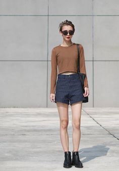 Woman with short hair and sunglasses wearing a crop top and striped shorts outdoors