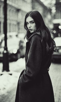 Woman with long hair in a winter coat on a street in black and white