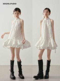 Two women in white halter neck dresses and black boots posing indoors