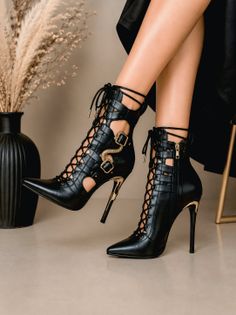 Woman wearing black lace-up high heels with gold accents and cut-out design