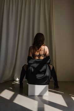 Woman in black lingerie and robe, sitting with her back to the viewer