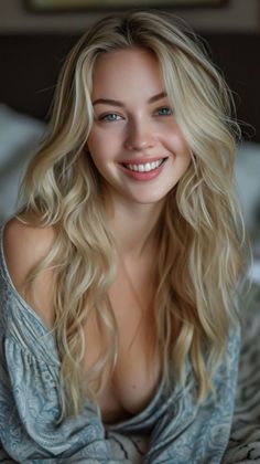Blonde woman with blue eyes smiling, wearing a loose top with cleavage visible