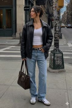 Woman in a black leather jacket and blue jeans on a city street