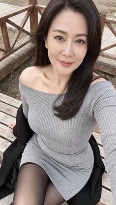 Woman in a grey off-shoulder dress and black tights sitting outdoors