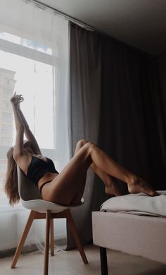 Woman in black lingerie stretching on a chair in a bedroom