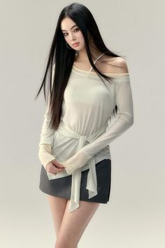 Woman with long black hair wearing an off-shoulder top and mini skirt in a studio