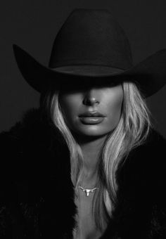 Woman in a cowboy hat and fur coat with a bull skull necklace in black and white