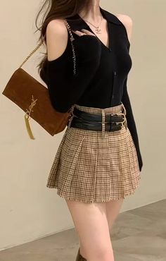 Woman in a black top and plaid skirt with a shoulder bag