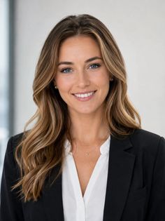 Woman with long blonde hair and blue eyes wearing a suit and white shirt