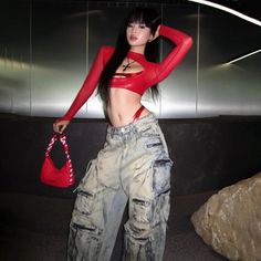 Woman in a red crop top and baggy jeans with a red thong visible