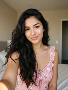 Woman with long dark hair wearing a pink daisy print dress indoors
