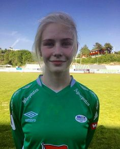 Young woman in a green soccer jersey on a sunny outdoor field