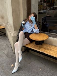 Woman in a blue striped shirt and brown skirt sitting at an outdoor cafe
