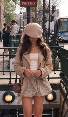 Woman in a beret and trench coat standing near a metro station entrance