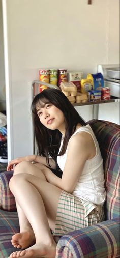 Woman with long dark hair sitting on a plaid couch indoors