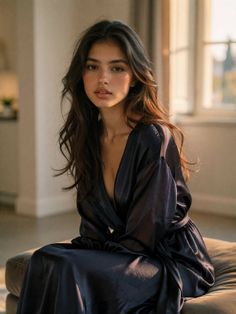 Woman with long dark hair wearing a robe indoors with soft lighting