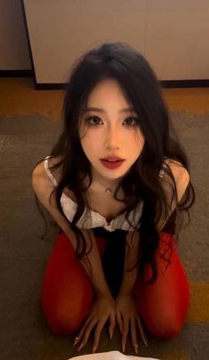 Woman with long dark hair and red tights in a provocative pose indoors
