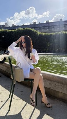 Woman in a white shirt and sunglasses sitting outdoors on a sunny day