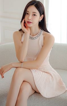 Woman in a pink dress with a jeweled neckline sitting on a couch
