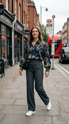 Woman in a patterned shirt and wide leg pants walking on a city street