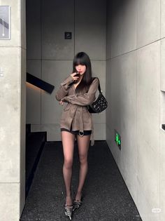 Woman with long black hair wearing an oversized shirt and black shorts indoors