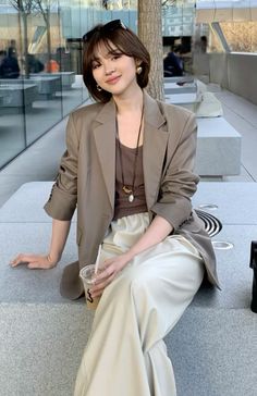 Woman with short hair and a blazer sitting outdoors with a drink