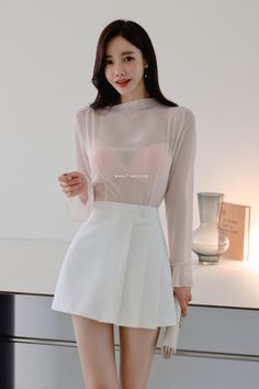 Woman in a sheer top and white skirt with a pink bra visible underneath