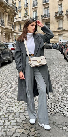 Woman in a long coat and wide leg pants on a cobblestone street
