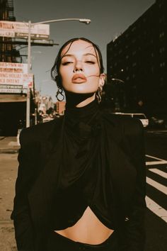 Woman in a black outfit with exposed midriff on a street with dramatic lighting