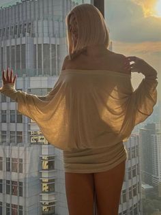 Woman with blonde hair in an off-shoulder top against a city sunset