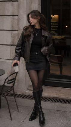Woman in a leather jacket and mini skirt holding a coffee cup outdoors