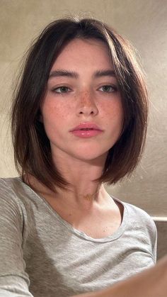 Woman with short brown hair, freckles, and green eyes wearing a gray shirt