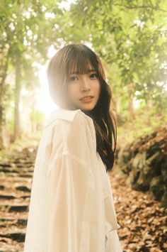 Woman with long hair in a white shirt outdoors with soft backlight