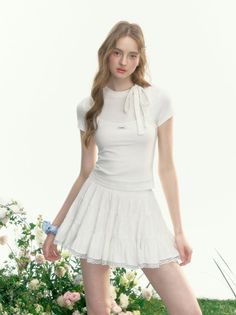 Woman in a white top and mini skirt standing among flowers
